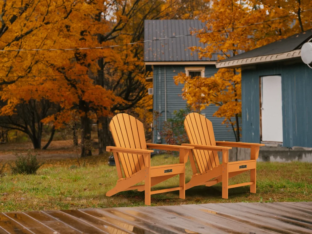 Two orange traditional Adirondack chairs in patio on Autumn
