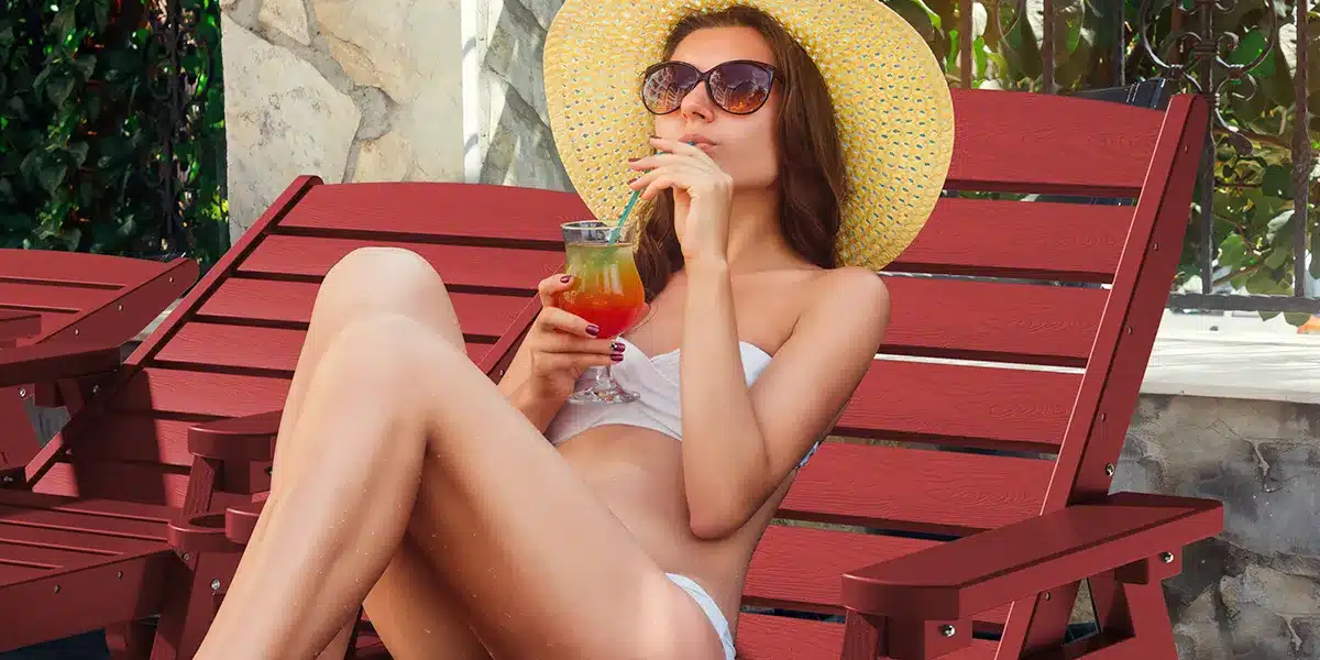 Woman enjoying drink while sitting on red lounge chair
