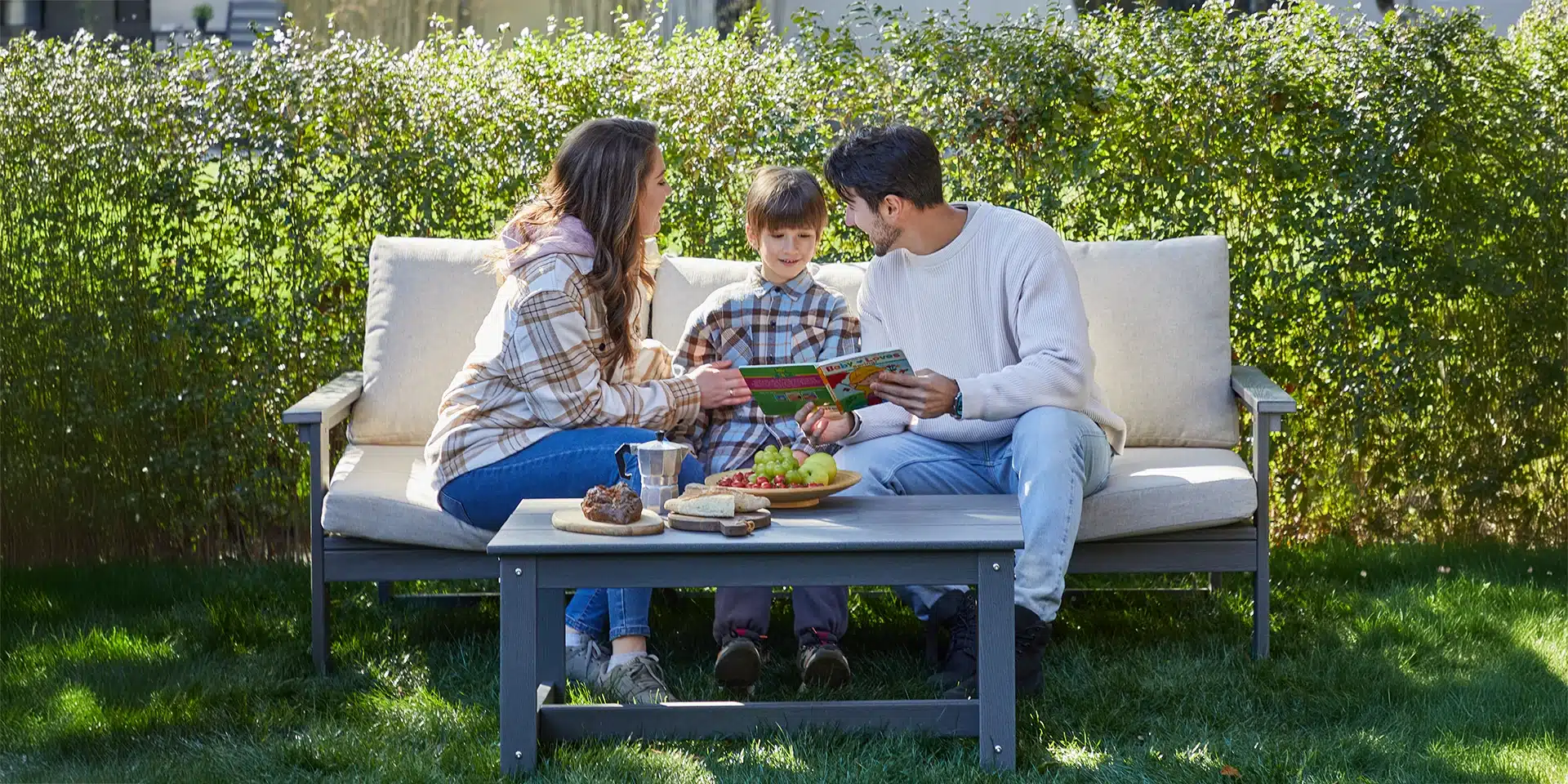 A family of three sitting on the plastic 3 seater outdoor sofa set